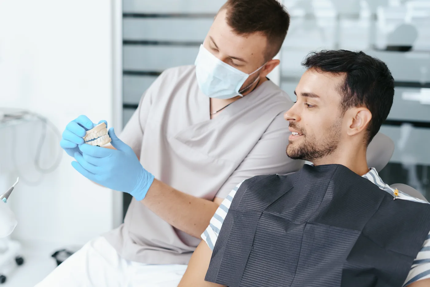 A dentist showing a patient a model of their teeth before a consultation